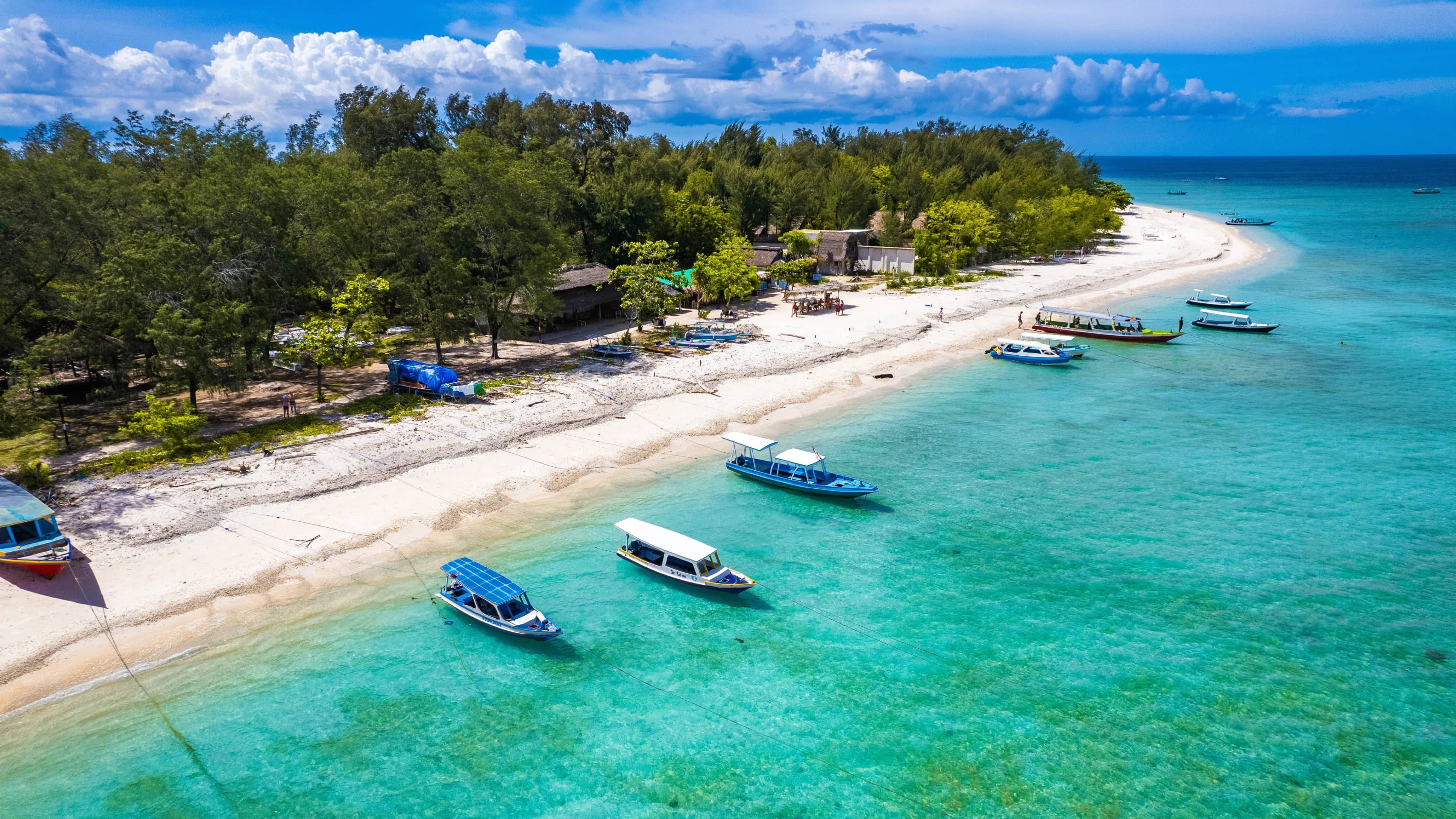Aerial view of Gili Trawangan's beach with boats anchored in clear shallow water, Lombok